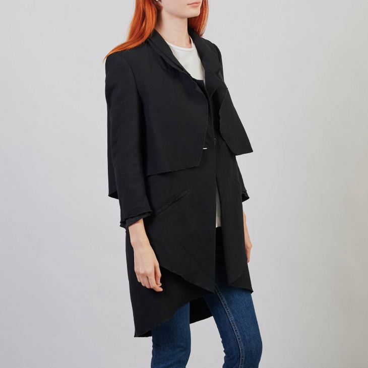 Черное пальто с асимметричными деталями на одной пуговице.